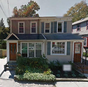 A two-story duplex with twin front doors and a small front garden