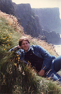 Brian lying in the long grass on a clifftop above the sea
