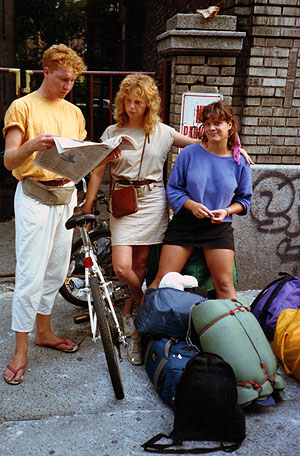 Three Danish travelers with bicycles and backpacks reading a map on a New York sidewalk