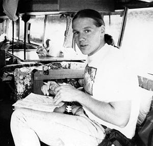 Black-and-white photo of Brian in the driver's area of the bus, going over a list