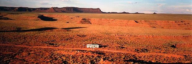 The bus, tiny in a vast red desert, with mesas on the horizon