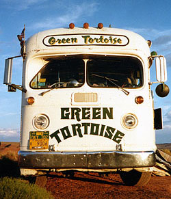 The front of a white bus with GREEN TORTOISE painted in bold letters below the windshield