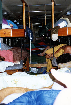 Passengers asleep in sleeping bags on the bus's platforms and bunks