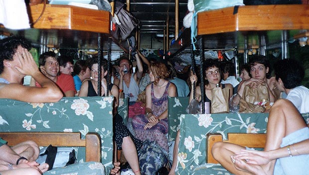 Passengers sitting and lounging on cushioned platforms inside the bus