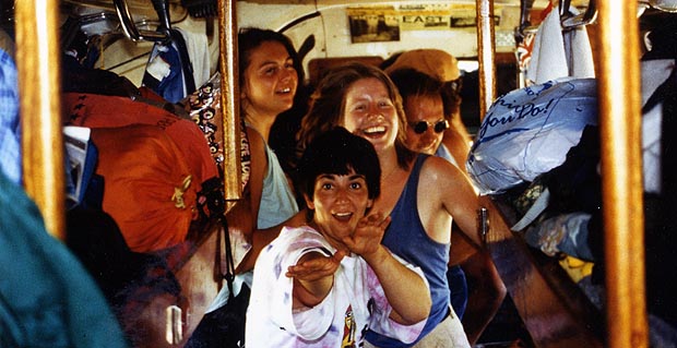 A group of passengers crowded together and laughing inside the bus